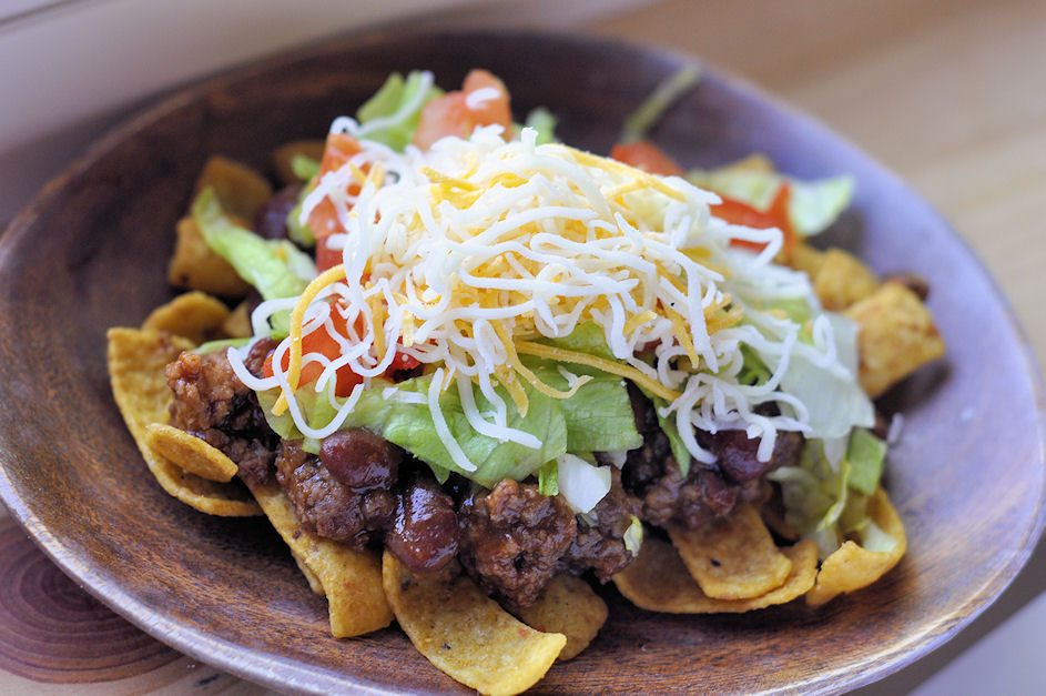 Haystack salad with chili and shredded cheese over corn chips