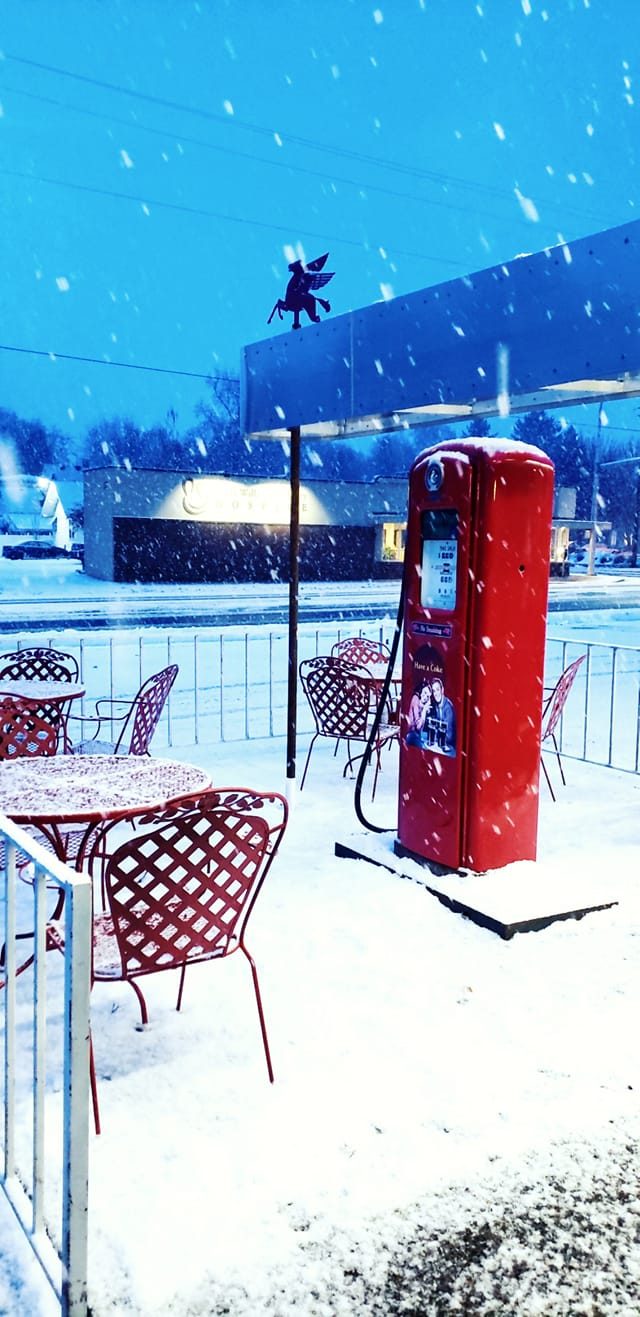 Snowy patio at Tony's with red tables and a vintage red gas pump — cold-weather vibe